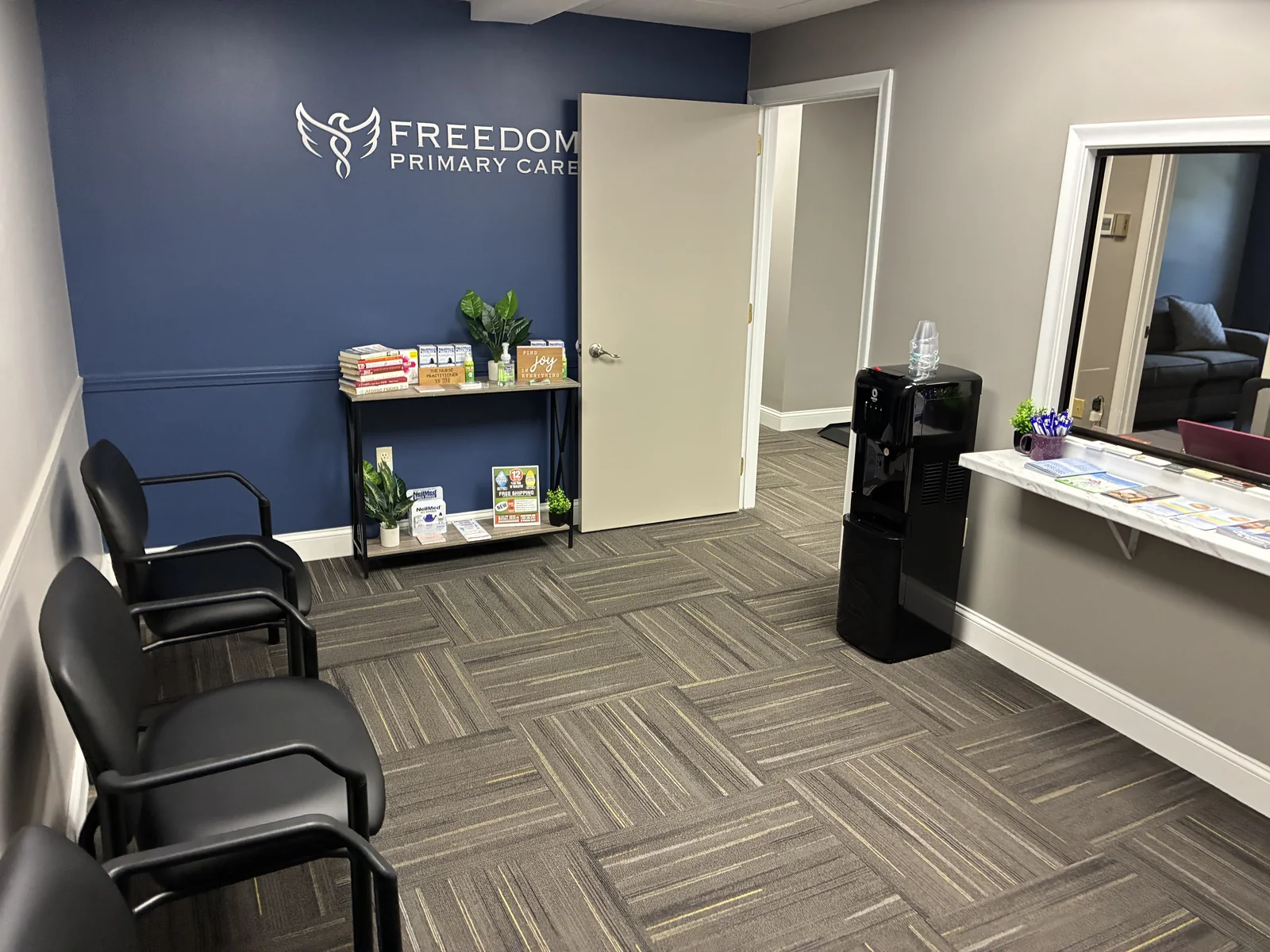 Waiting room and reception area with the Freedom Primary Care logo on a blue wall
